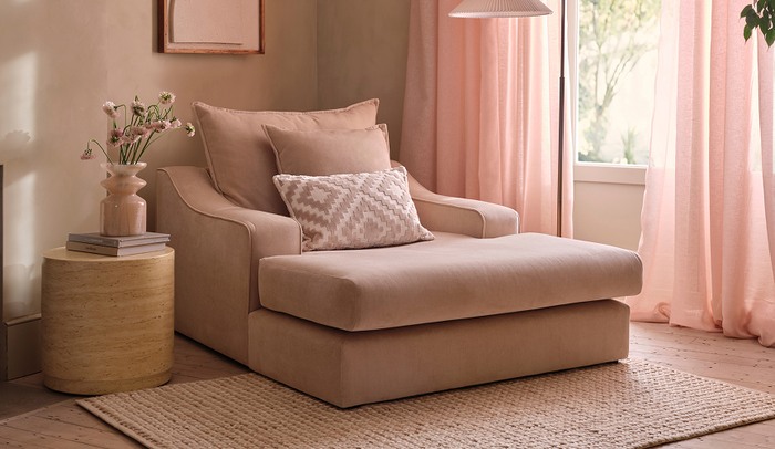 House Beautiful Maura cuddle lounge chair in a neutral cosy room with pink curtains and a light marble side table
