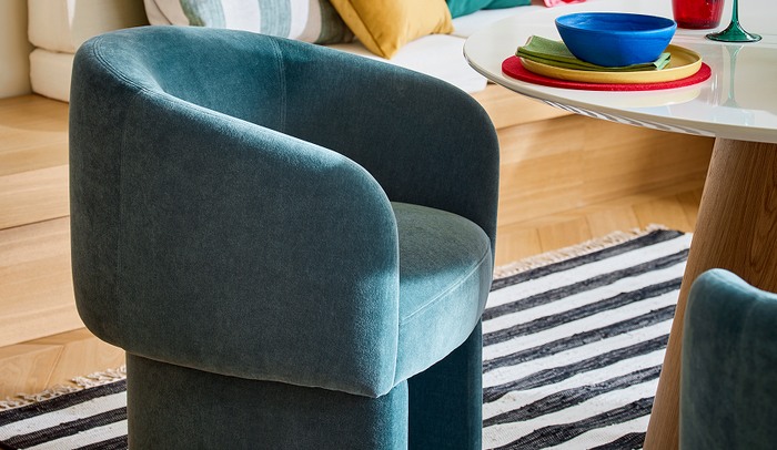 Blue winged chair next to an oak and white gloss dining table with colourful tablewear