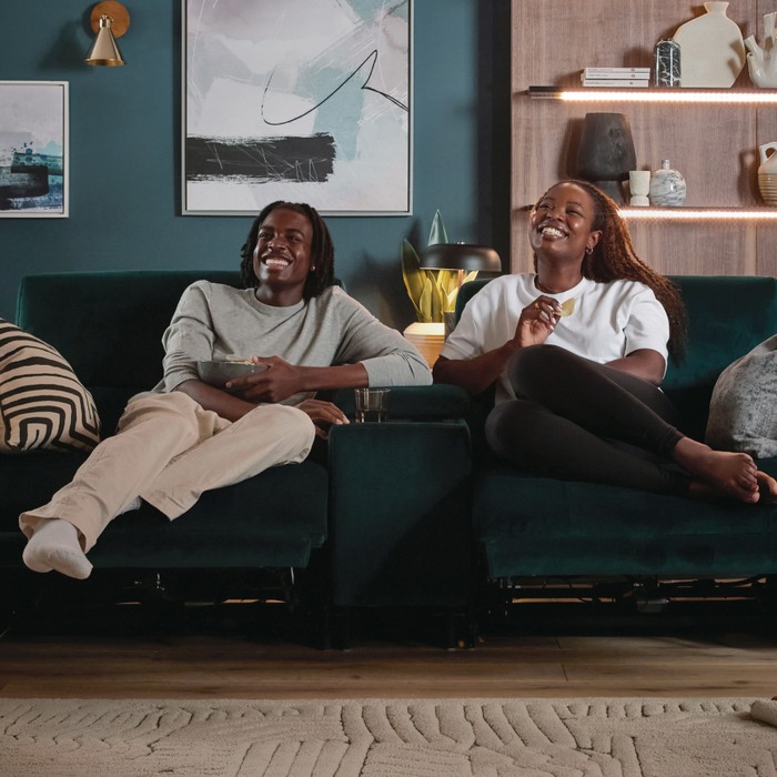 young couple laughing and watching tv on a sofa