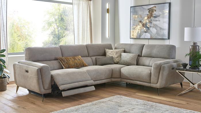Beige recliner corner sofa with metal legs in a bright living space with yellow and neutral scatters and accessories