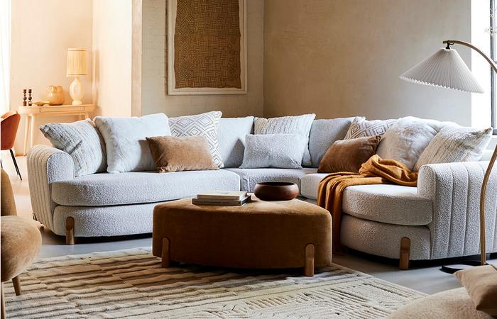 boucle curved sofa with wooden legs and a brown footstool