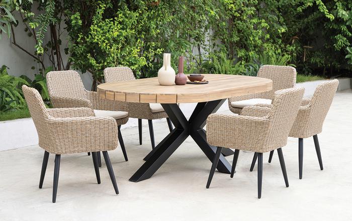 Round wooden outdoor dining table with black legs and 6 cream rattan chairs with black feet
