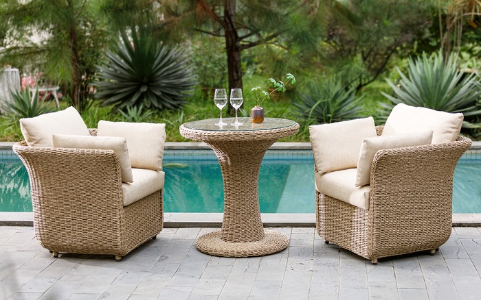 beige rattan bistro set next to a pool