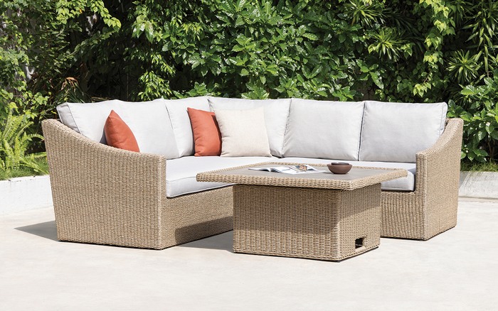 beige rattan garden outdoor sofa with matching table on a pattern outdoor rug