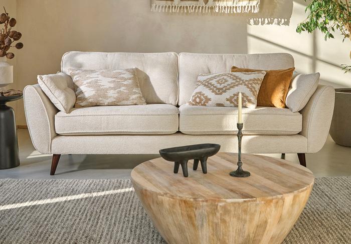 White boucle mid century sofa with light wood coffee table finished with neutral patterned and orange scatter cushions