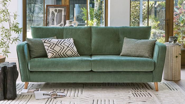 Sage green fabric sofa with wooden mid century legs and monochrome scatter cushions