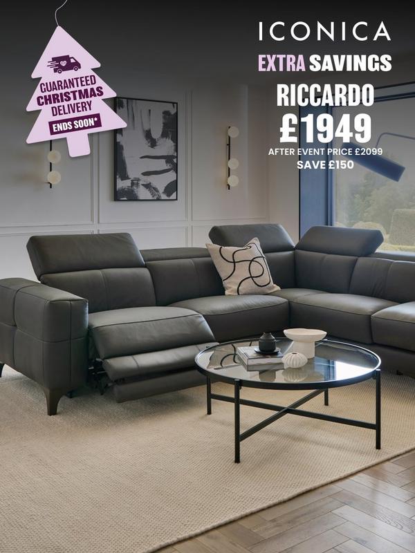 Black leather corner sofa with reclining features and integrated footstool on side