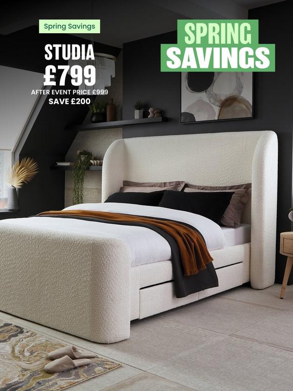 Double bed in white boucle fabric in a dark bedroom with floor to ceiling windows