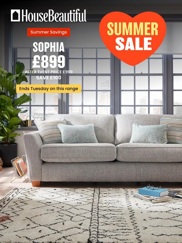 Light grey sofa with pastel coloured scatter cushions in front of crittal style windows