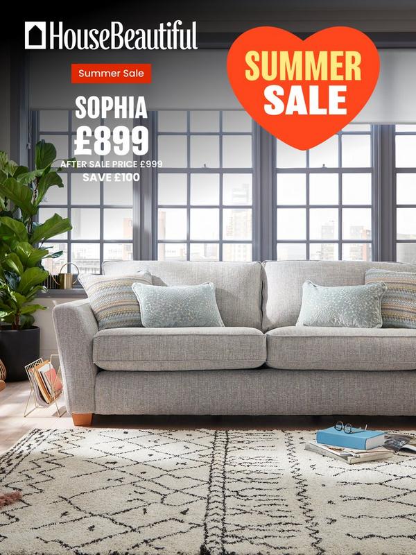 Light grey sofa with pastel coloured scatter cushions in front of crittal style windows