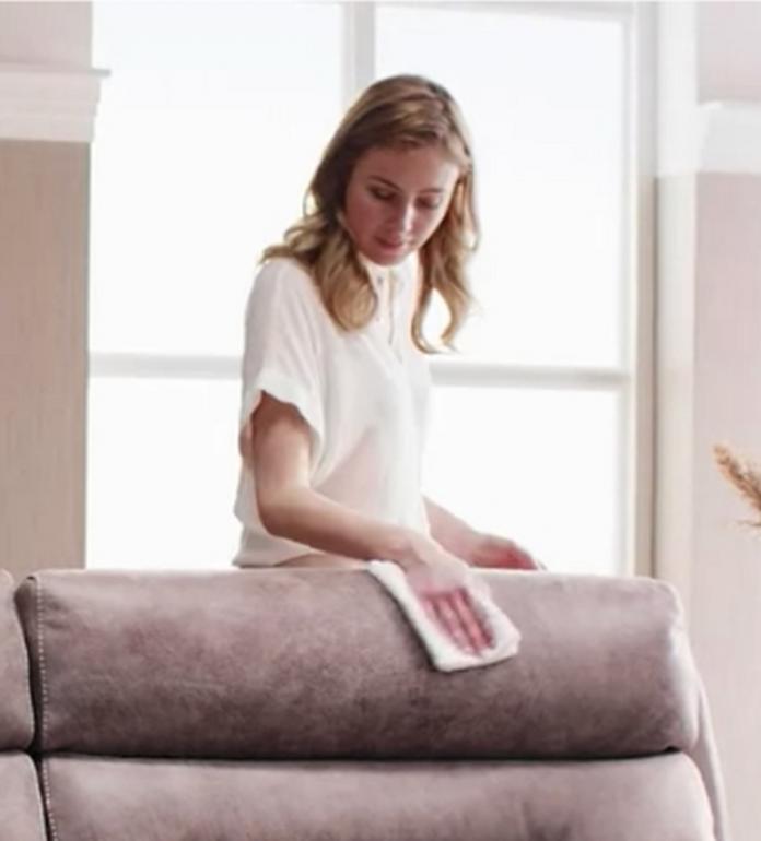 young women cleaning leather sofa