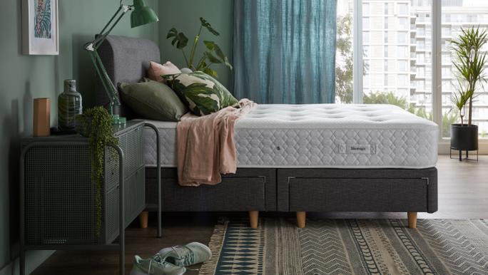 Grey divan bed with a silentnight mattress topped with a pink throw in a cosy bedroom with green walls