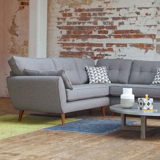 light grey corner sofa with wooden slim angled legs on a colourful rug next to a brick wall