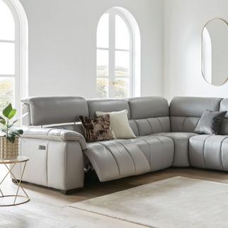 Light grey leather recliner sofa in a bright white living room with a fluffy white rug