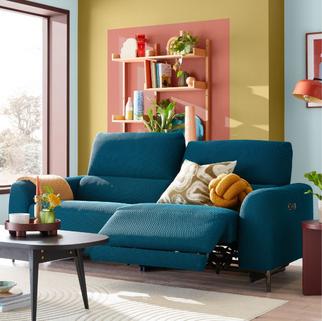 Blue recliner sofa against a colourful blue, yellow and blue living room wall and a large window