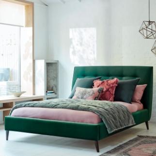 Green buttoned bed frame with black angled legs finished with green and pink bedding