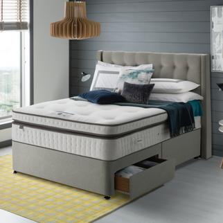 Light grey bed frame with under bed drawer storage with a plain mattress on top finished with a yellow patterned rug