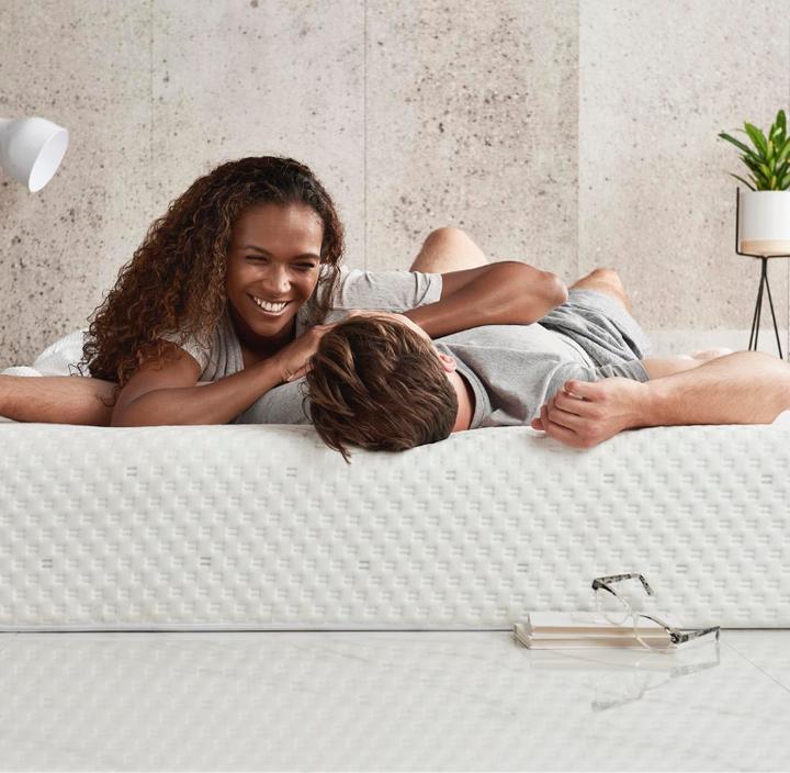Young couple laying and laughing on a bed