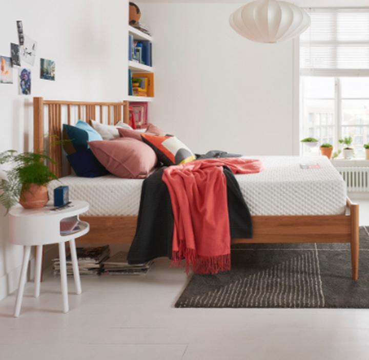 A Silentnight mattress on top of a wooden bed frame finished with black and red throws and cushions