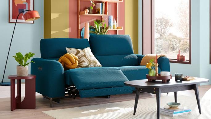 Blue recliner sofa with orange knot cushions in a colour and bright living room
