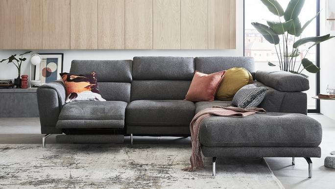 Grey leather recliner corner sofa with coloured scatter cushions and a pink throw