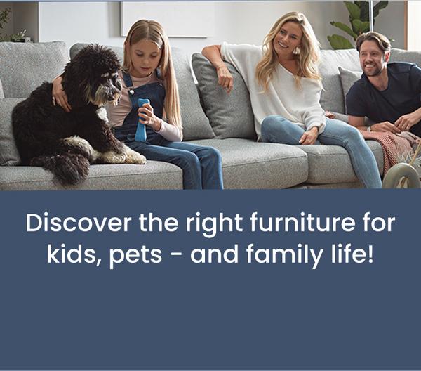 a young family and their pet dog laughing and playing whilst sat on a sofa