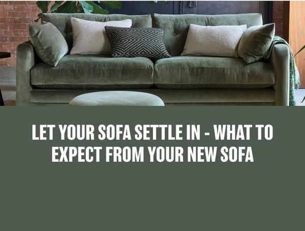 dark green fabric sofa with white and monochrome cushions next to a brick wall