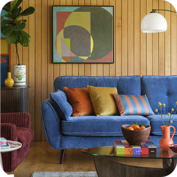 Blue sofa against a wooden panelled wall finished with multi coloured scatter cushions 