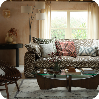 Zebra print sofa with patterned scatter cushions with a dark wood coffee table and accent chair
