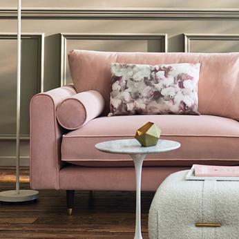 Pink velvet sofa with round bolster and floral cushion