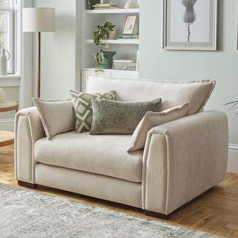 cream armchair with green scatter cushions on a wooden floor