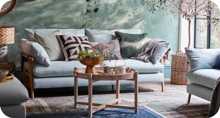 Light blue sofa with wooden legs in a bright and airy living room with a blue wall