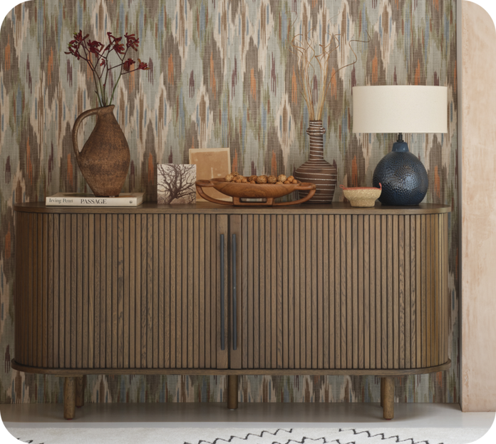 Dark wood panelled sideboard against a patterned wall with various ornaments