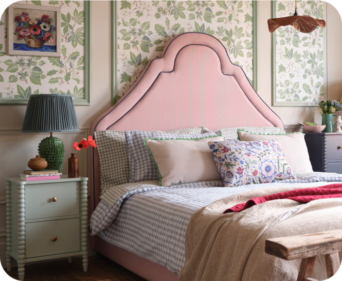 red stripe bed with blue trim against a green floral wall and patterned scatter cushions and bedding