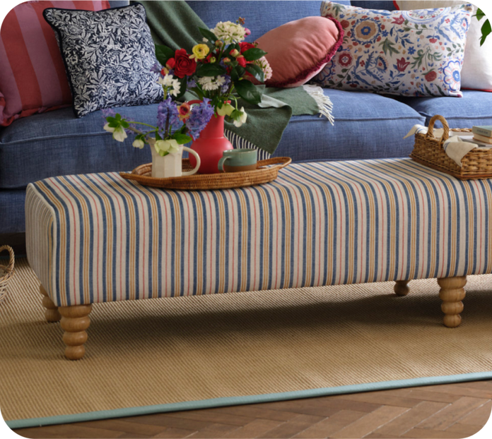 footstool with blue and red stripes on a yellow rug with blue border
