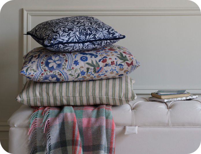 a pile of pattern scatter cushions on a buttoned light grey footstool
