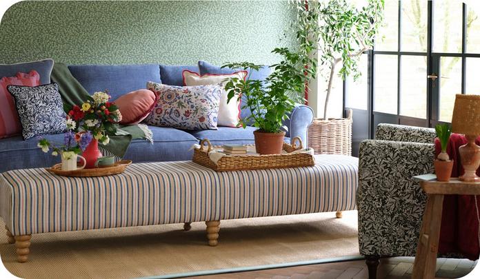 blue sofa against a green floran wall with stripy footstool and pattern scatters