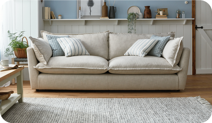 Beige sofa with blue patterned scatter cushions on a wooden floor against a panelled and blue wall
