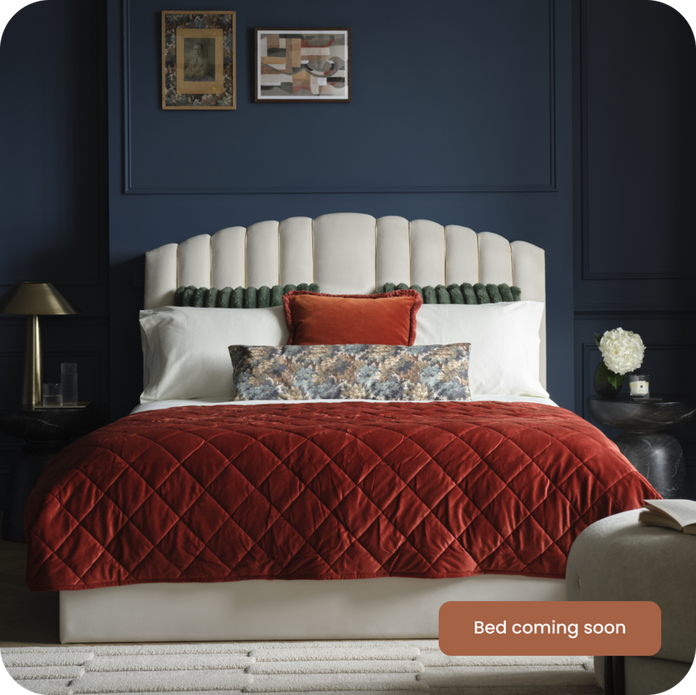 White padded be against a navy blue wall finished with white and red bedding