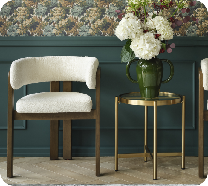 Dark wood dining chair with boucle seat padding next to a gold side table against a patterned wall