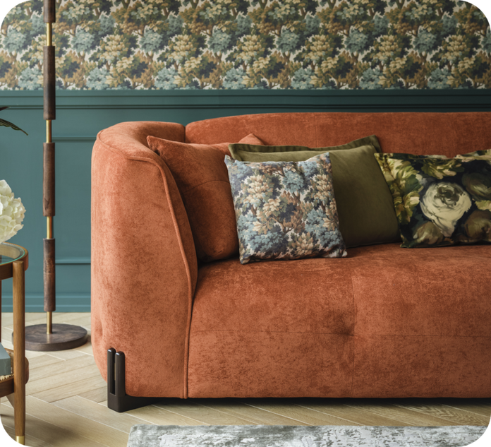 Ruse curved sofa against a teal and floral paper wall on a wooden floor