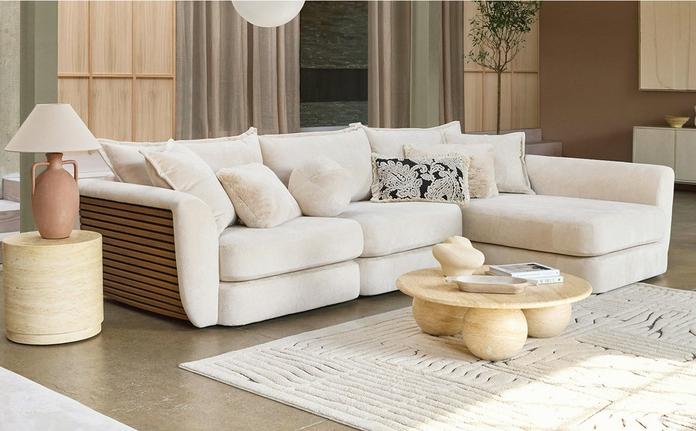 white corner sofa with wooden panelling to the side finished with fluffy cushions next to a fluffy rug