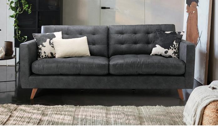 dark grey faux leather sofa with buttoned seat back and cow print scatter cushions