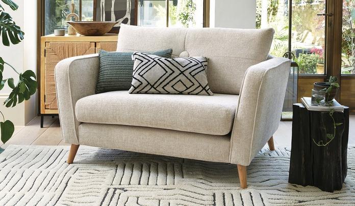 beige cuddler sofa with green and monochrome cushion