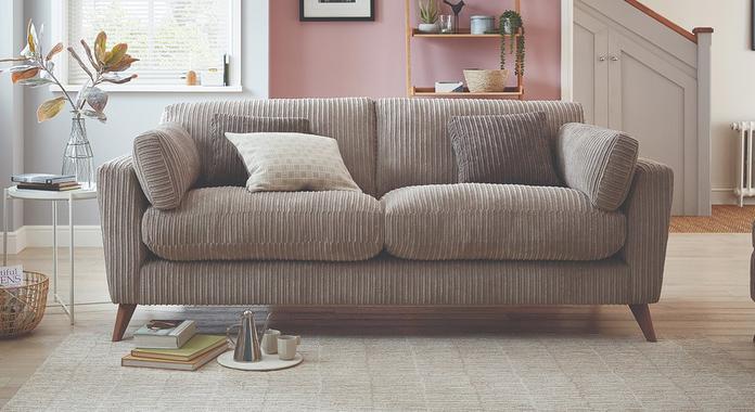 Light brown jumbo cord sofa with angled wooden legs on a fluffy beige rug