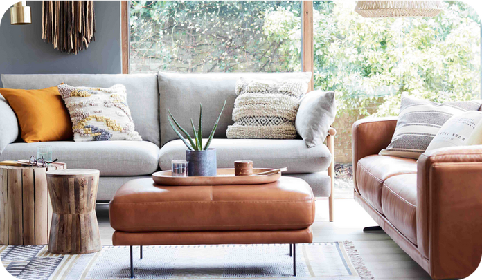 Grey fabric sofa with a wooden frame alongside a brown leather sofa against a large window