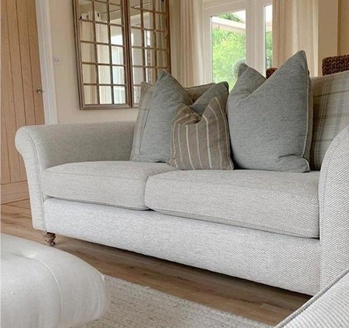 a light grey chesterfield style sofa with chopped scatter cushions on a wooden floor