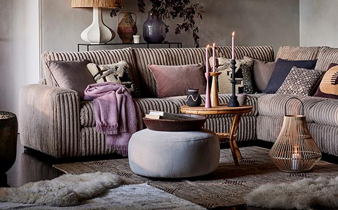 Cosy living room finished a purple throw and scatter cushions with a wooden table topped with candles