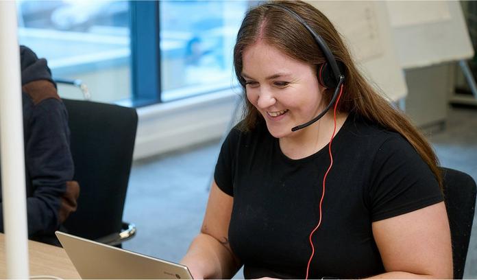 a smiling women with an over head headphone talking to a customer