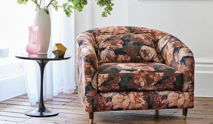 multi coloured floral tub chair next to a black side table on a dark wood floor